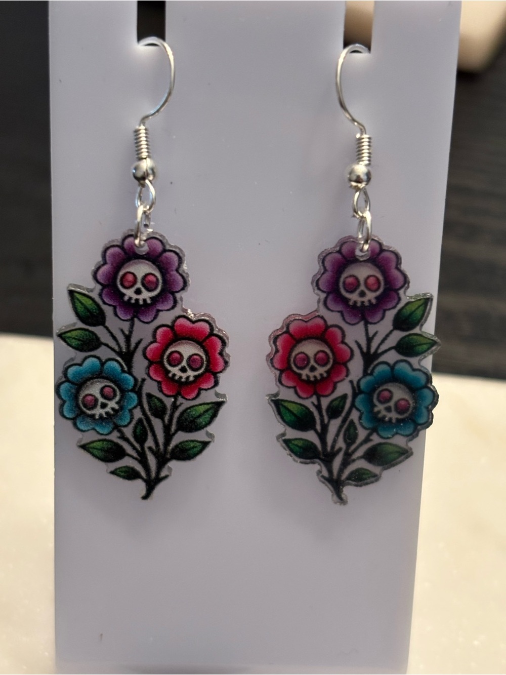 Title: Skull Flowers Acrylic Dangle Earrings | Three White Skulls in Purple Pink